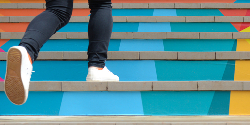Osoba kráčející po barevných schodech